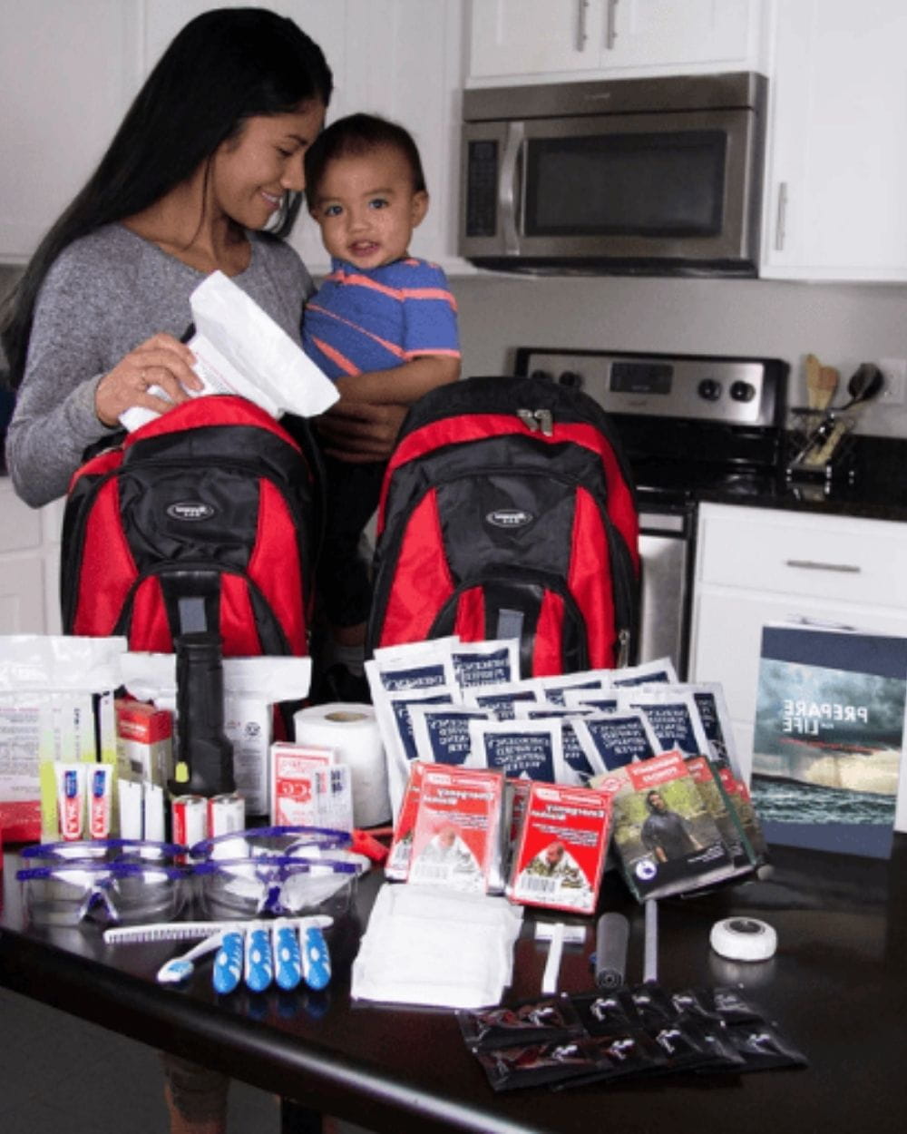 mom holding child and looking at contents of family kit on counter