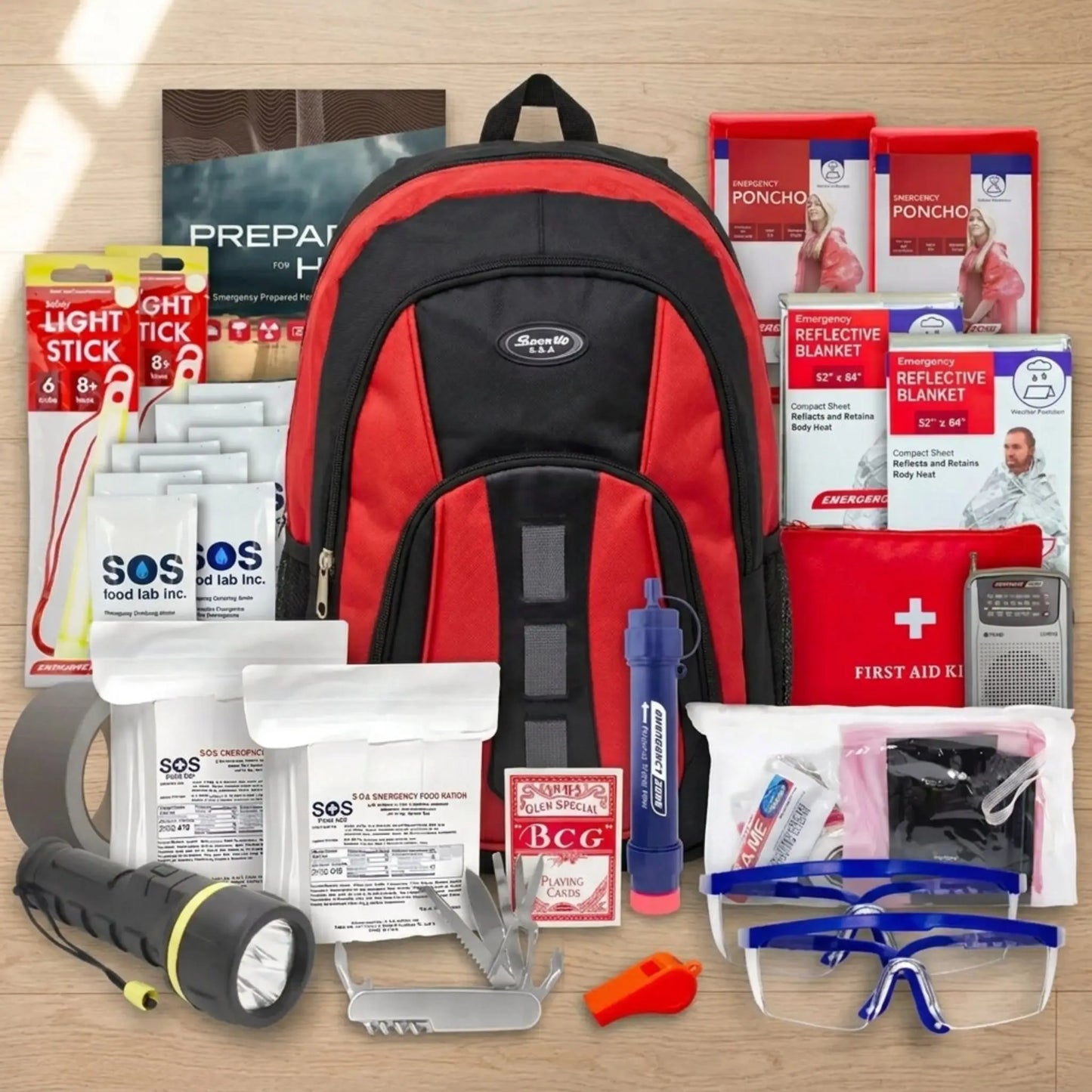 Emergency preparedness kit with a red and black backpack, flashlight, first aid kit, and other supplies on a wooden surface.