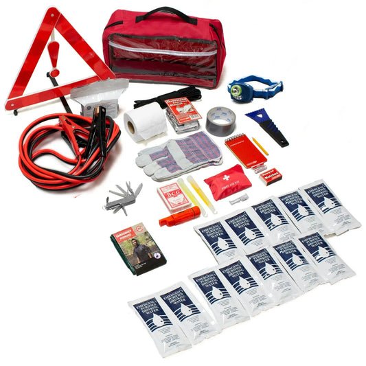 A comprehensive emergency preparedness kit laid out on a white background, featuring a red triangular warning sign, red and black jumper cables, a red zippered first aid bag, white gauze, a roll of tape, gray duct tape, a blue headlamp, a multi-tool, red and white bandages, and multiple small medical and utility pouches.