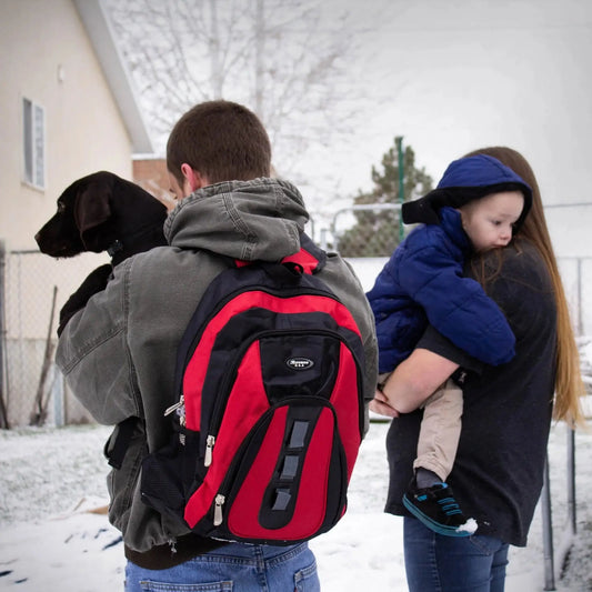 Family evacuating in winter with RapidShield 72-hour family emergency kit red backpack